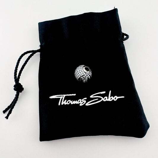 Silver zirconia charm Thomas Sabo displayed with a black branded pouch