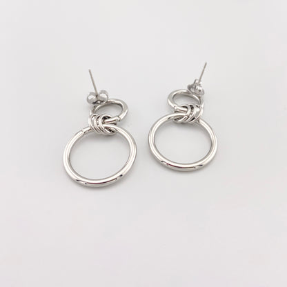 Сережки-кільця IRL на світлому мармурі, подвійні кола з полірованої сталі, чистий мінімалізм