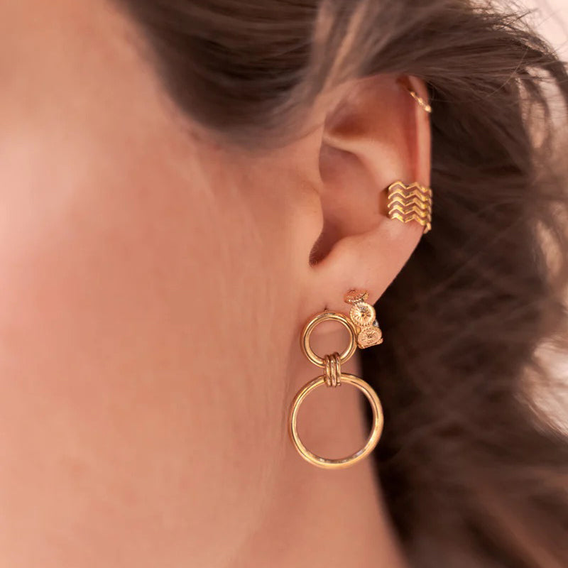 Aros dobles IRL en tono dorado en la oreja, círculos geométricos y brillo pulido, ajuste de perno