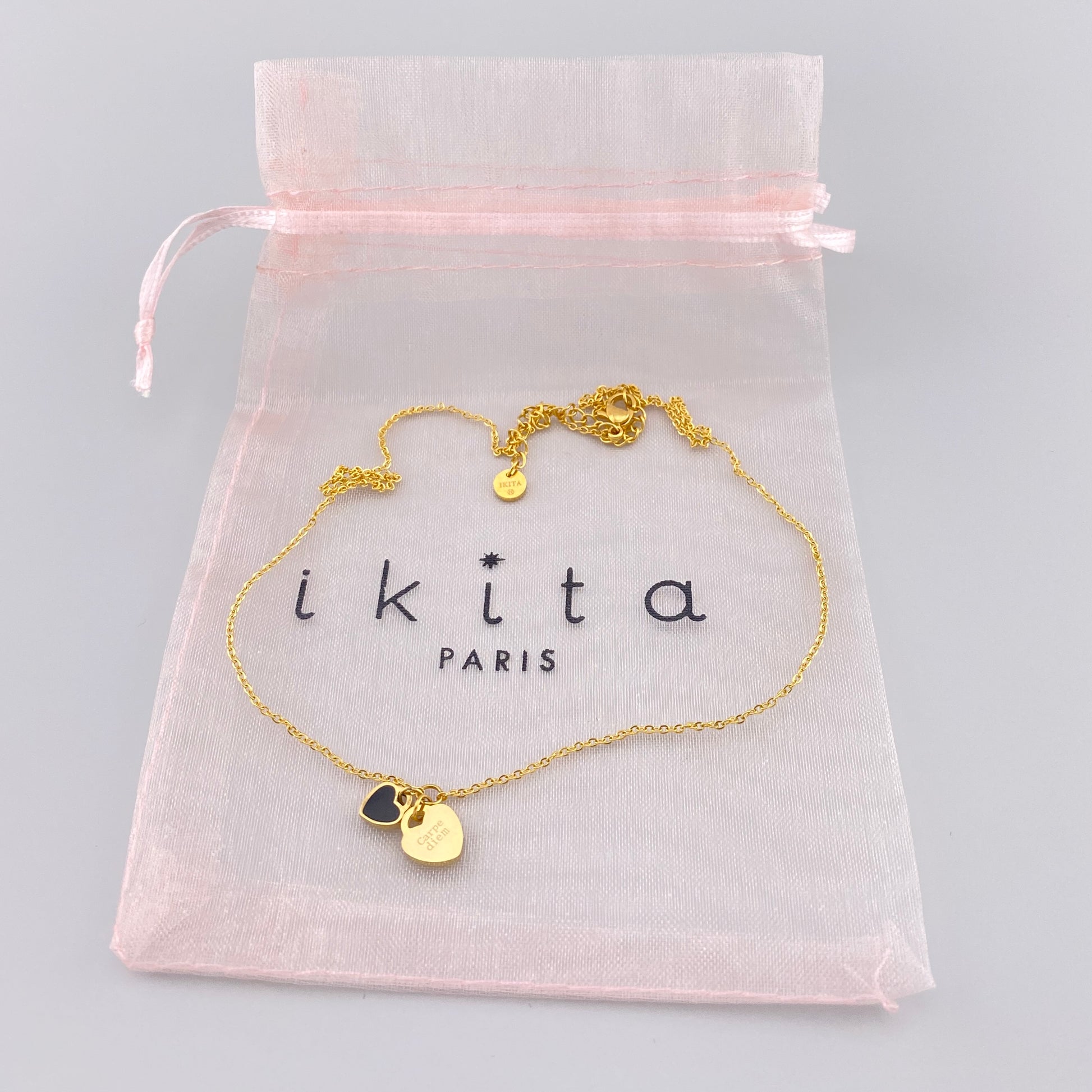 Collier Ikita doré à deux cœurs présenté dans une pochette rose