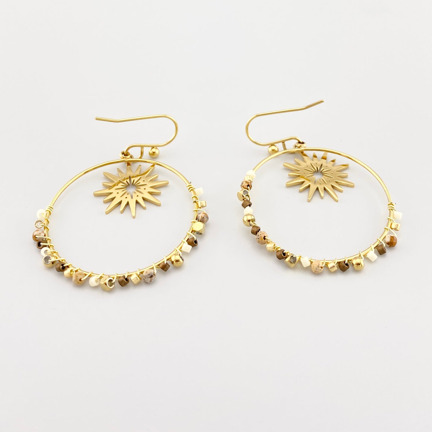 Pendientes dorados IRL con piedras naturales y estrella central sobre fondo blanco