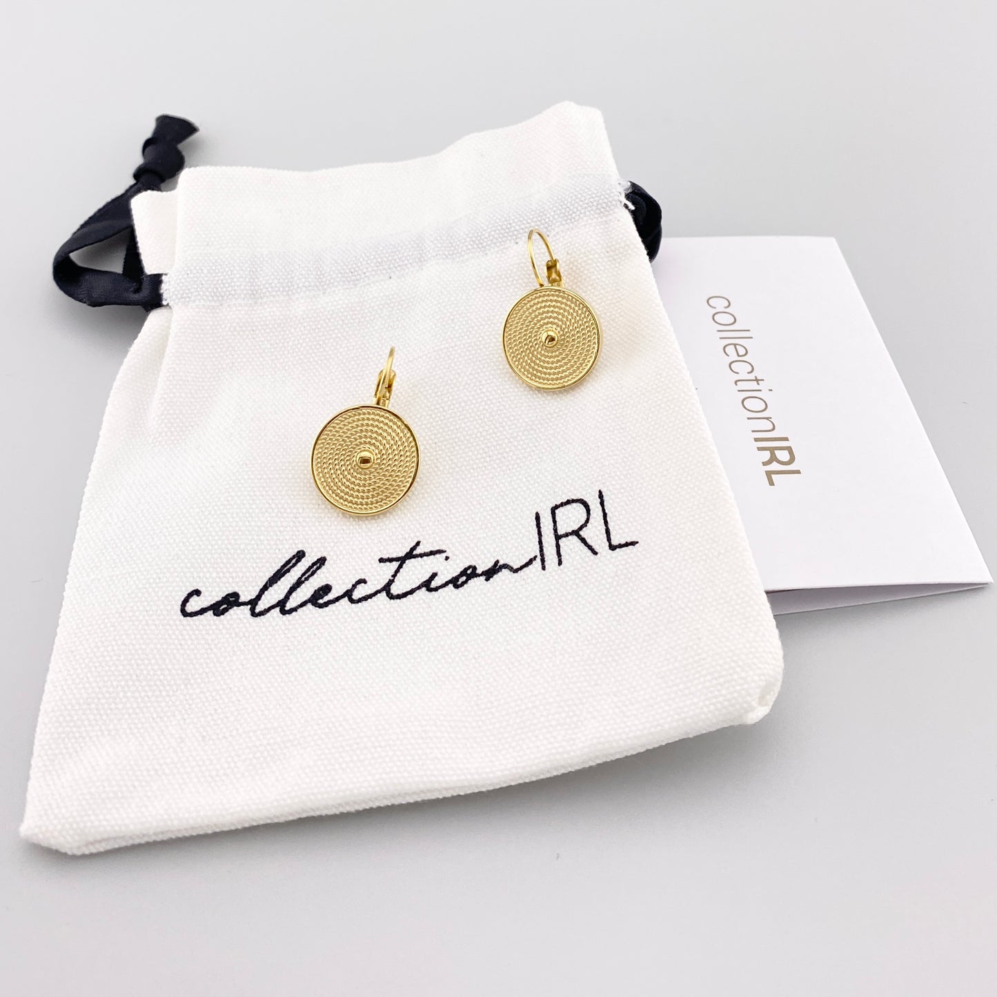 Gold IRL hoop earrings with spiral medallions presented with branded pouch