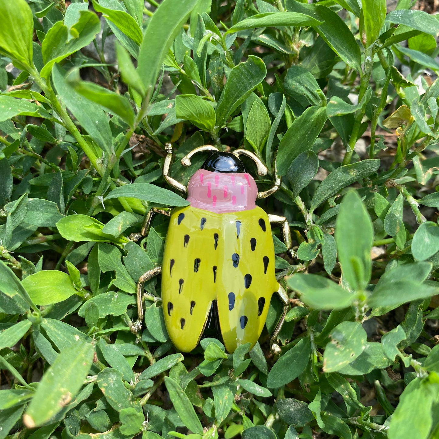 Broche scarabée verte posée sur des feuilles, style fantaisie avec détails dorés