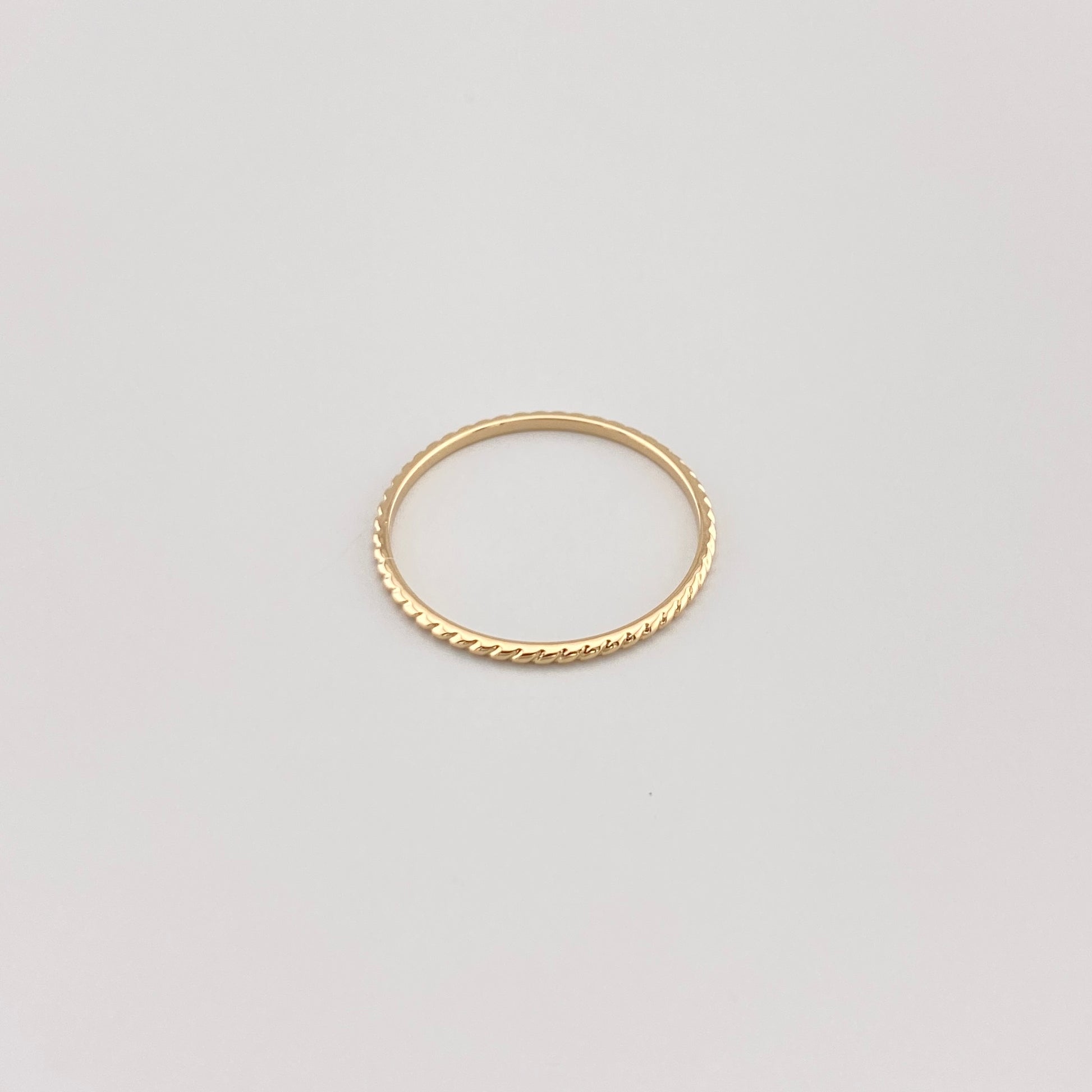 Minimalistyczny pierścionek IRL z pozłacaną powierzchnią na białym tle