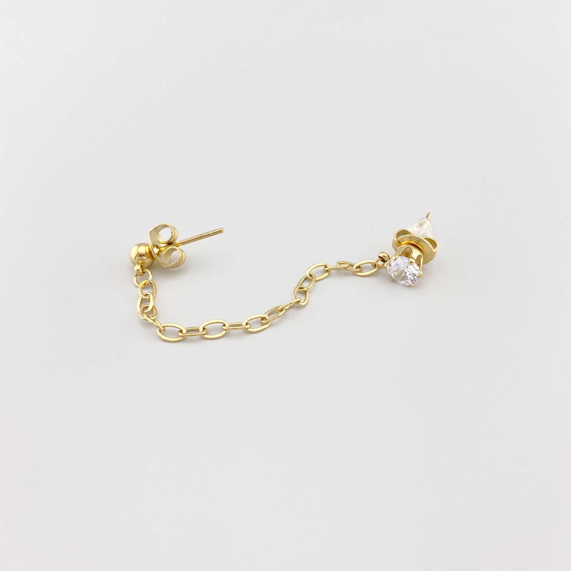 Kolczyk mono IRL z delikatnym łańcuszkiem i cyrkonią w złotym odcieniu, do dwóch dziurek