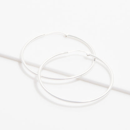 Boucles d’oreilles créoles IRL argentées présentées à plat sur fond clair