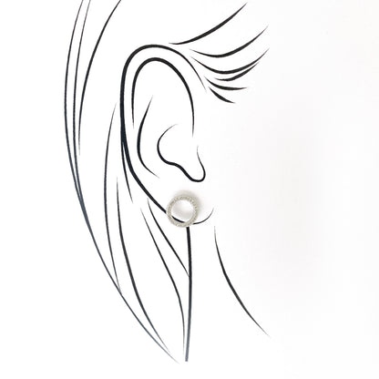 Silver hoop earrings with zirconia accents worn close to the ear